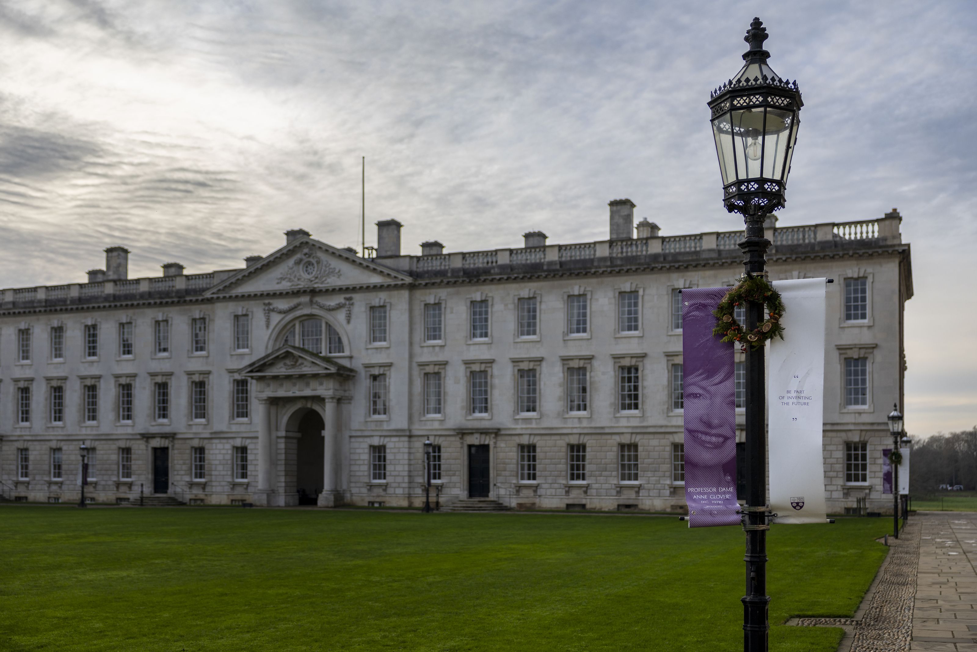 A white neoclassical building with a lamppost and banners in foreground