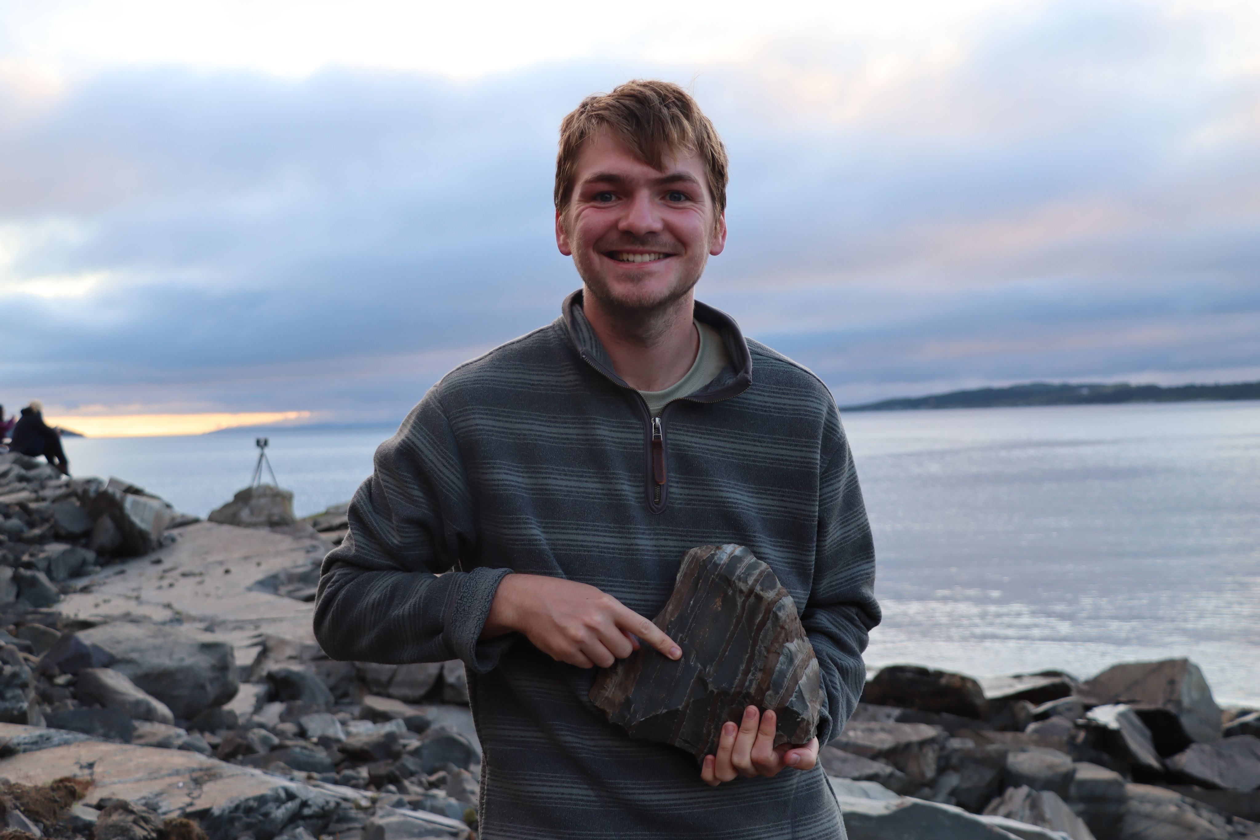 A researcher holds a fossil on a rocky coastline